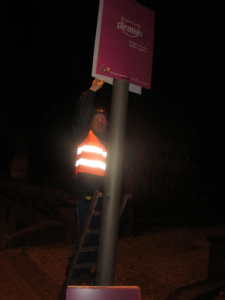 Puting up a placard on a lamppost at night