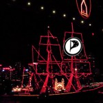 A ship with neon highlighted sails and PPUS logo sails under Sydney Harbour Bridge